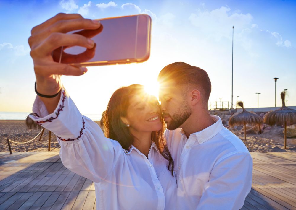 Couple young selfie photo in beach together vacation sunrise at Spain
