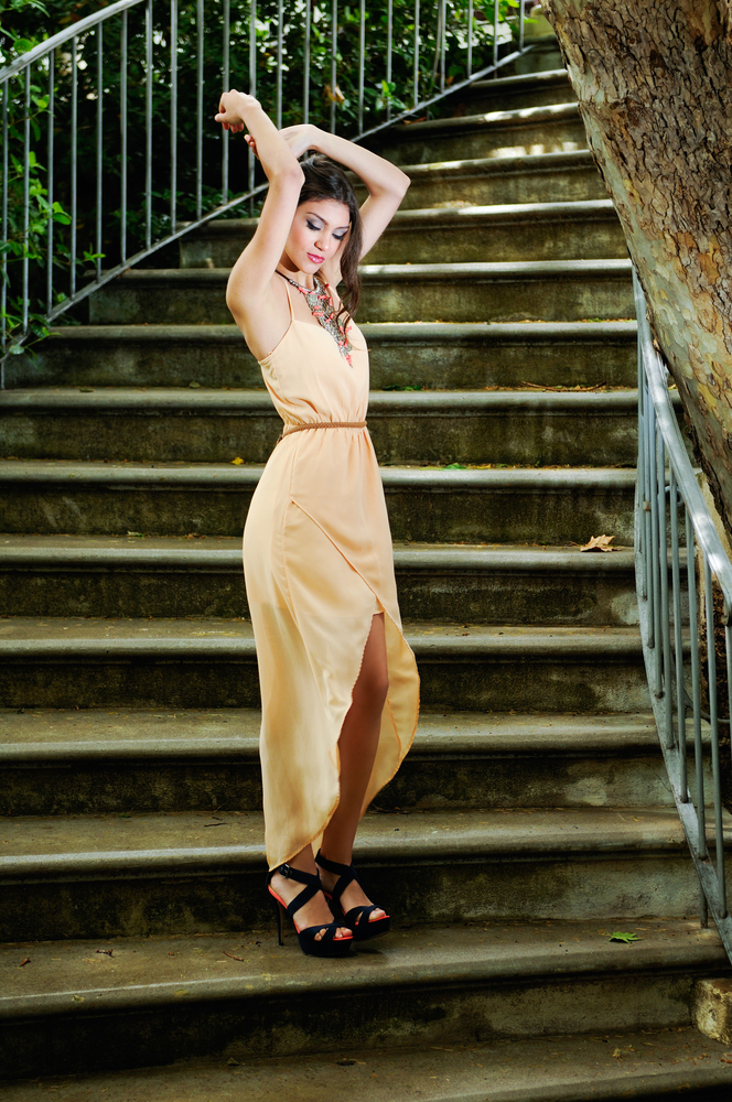 Portrait of a beautiful young woman, model of fashion, in a garden stairs.
