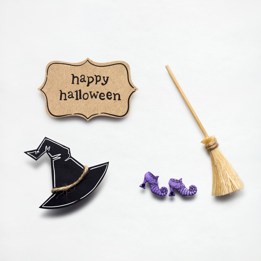 Creative halloween concept photo of witches hat and broom made of paper on white background.