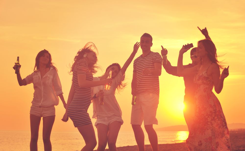 Group of young people enjoy summer  party at the beach on beautiful sunset