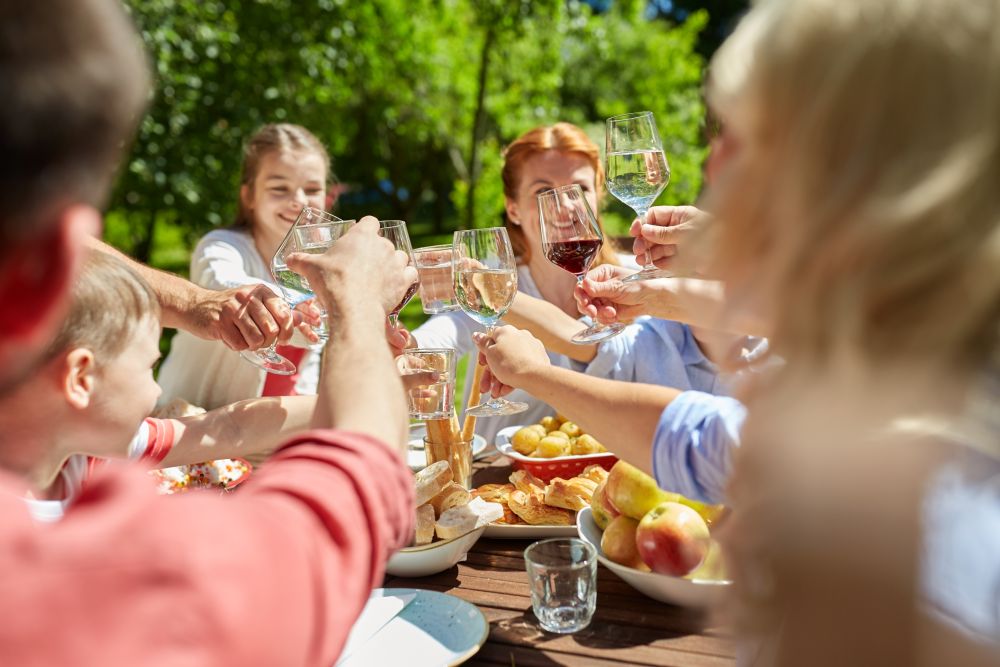 leisure, holidays and people concept - happy family having festive dinner or summer garden party and celebrating. happy family having dinner or summer garden party