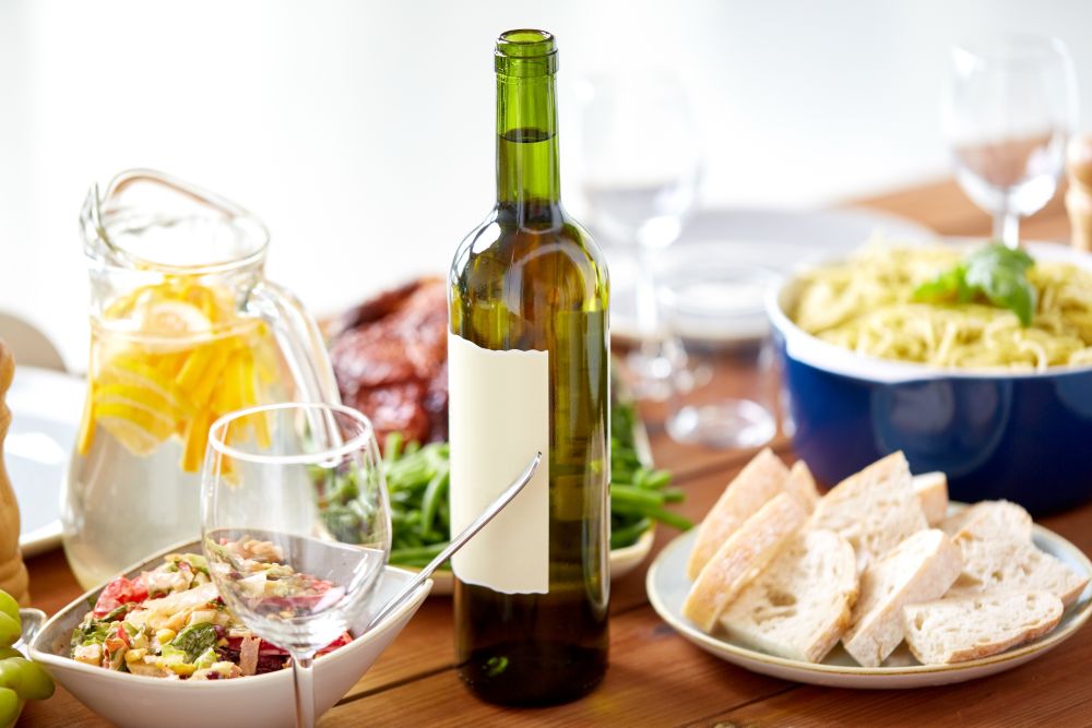 alcohol drinks, food and eating concept - bottle of wine and food on served wooden table. bottle of wine and food on served wooden table