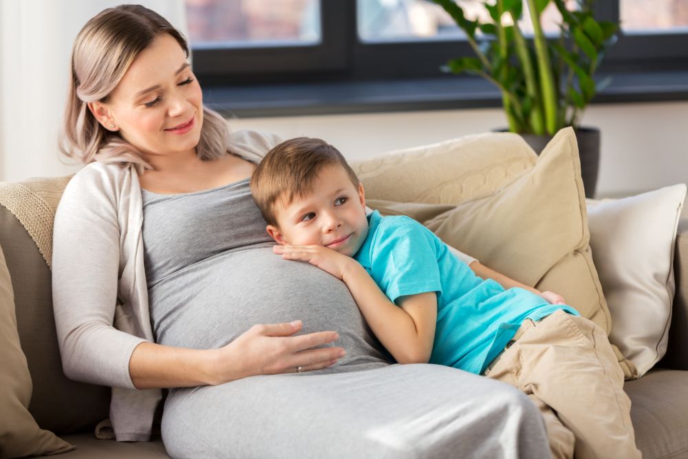 pregnancy, people and family concept - happy pregnant mother and little son hugging at home. happy pregnant mother and son hugging at home