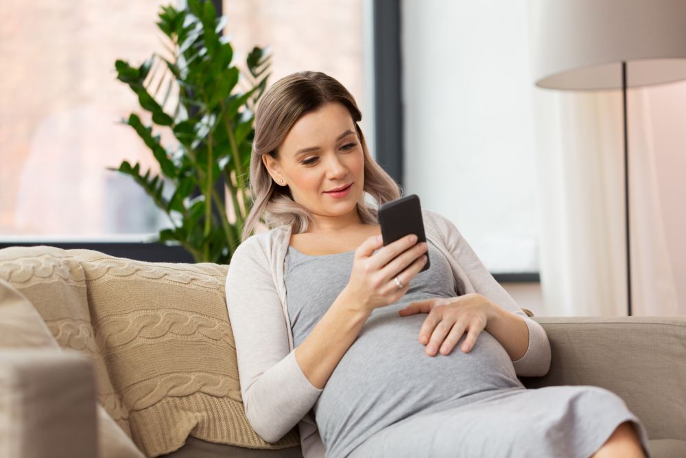 pregnancy, people and technology concept - happy pregnant woman with smartphone at home. happy pregnant woman with smartphone at home