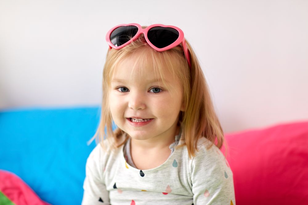 childhood and people concept - portrait of happy smiling little girl with heart shaped sunglasses. portrait of smiling little girl with sunglasses