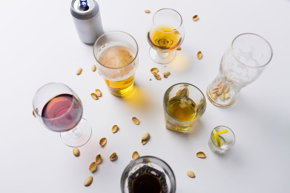 alcohol addiction and drunkenness concept - glasses of different drinks on messy table. glasses of different alcohol drinks on messy table. glasses of different alcohol drinks on messy table
