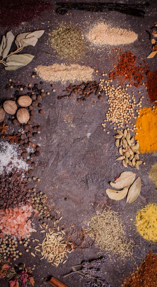 Flat lay composition frame of various spices  over brown slate background, top view. Flat lay spicy frame