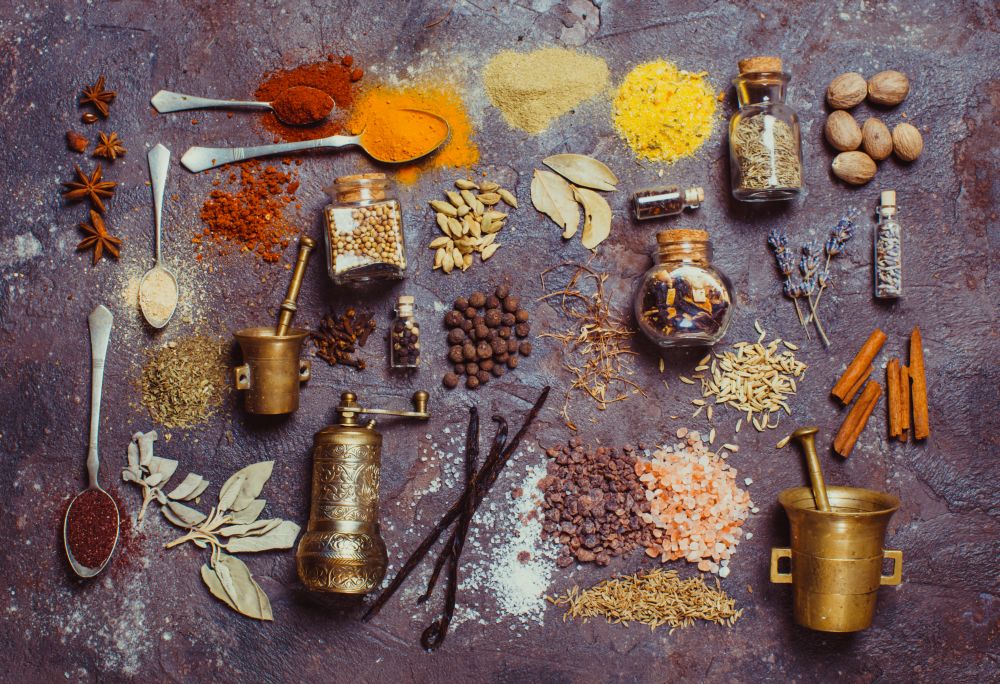 Flat lay composition of various spices and mortars over brown slate background, top view. Flat lay spices