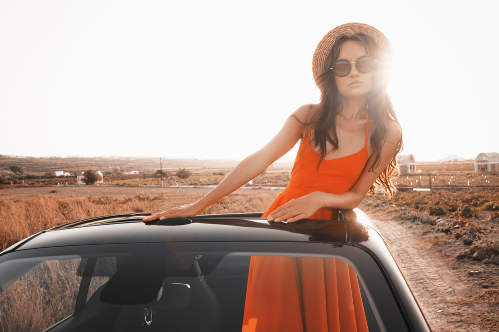 Outdoor lifestyle photo of beautiful happy woman in car cabriolet. Holiday and travel. Summer trip. Freedom, youth and carefree