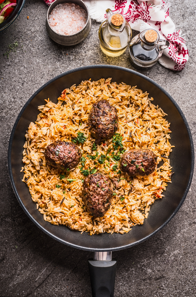 Meat balls and vegetables rice in pan served on gray stone kitchen table background, top view