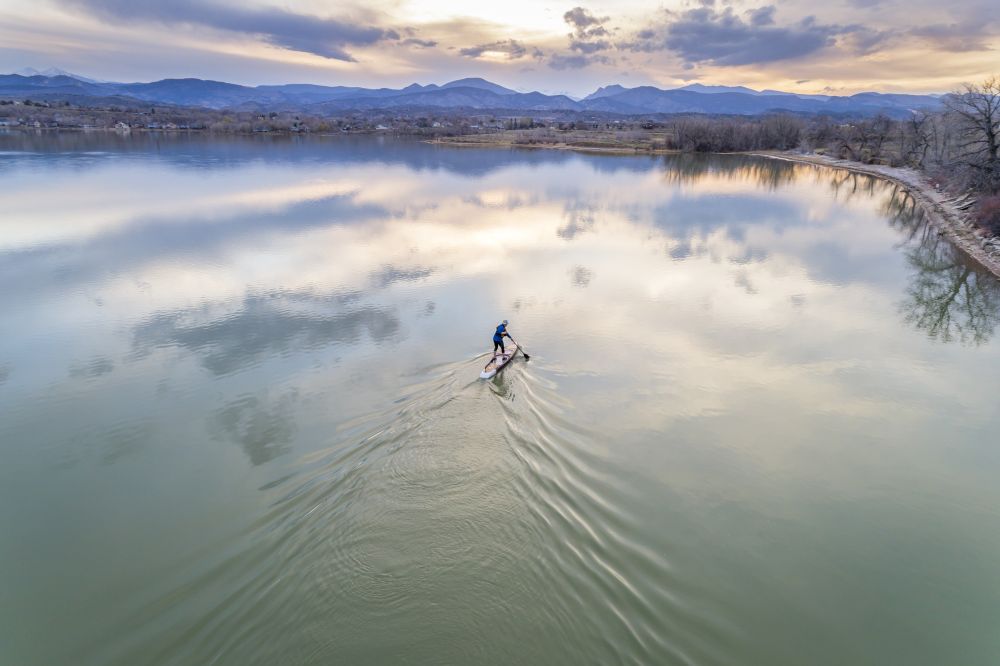 stand up paddleboard on lake - aerial view. paddling stand up paddleboard at dusk on a kae of foothills of Rocky Mountain in Colorado, early spring scenery, aerial view