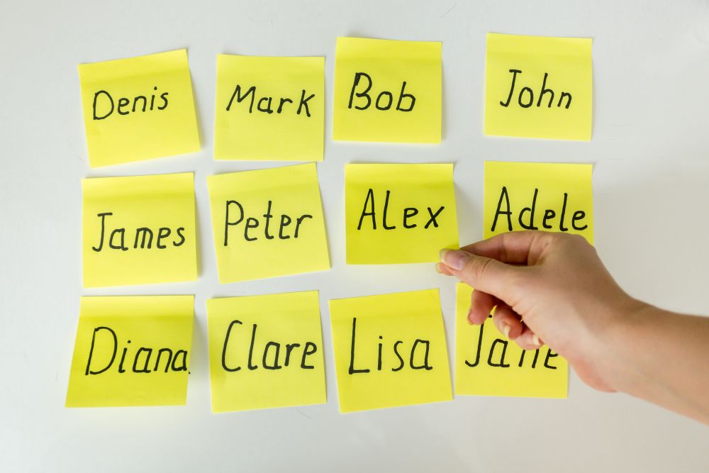 Conceptual photo of hard choice of baby&rsquo;s name. Closeup image of hand picking papers with names