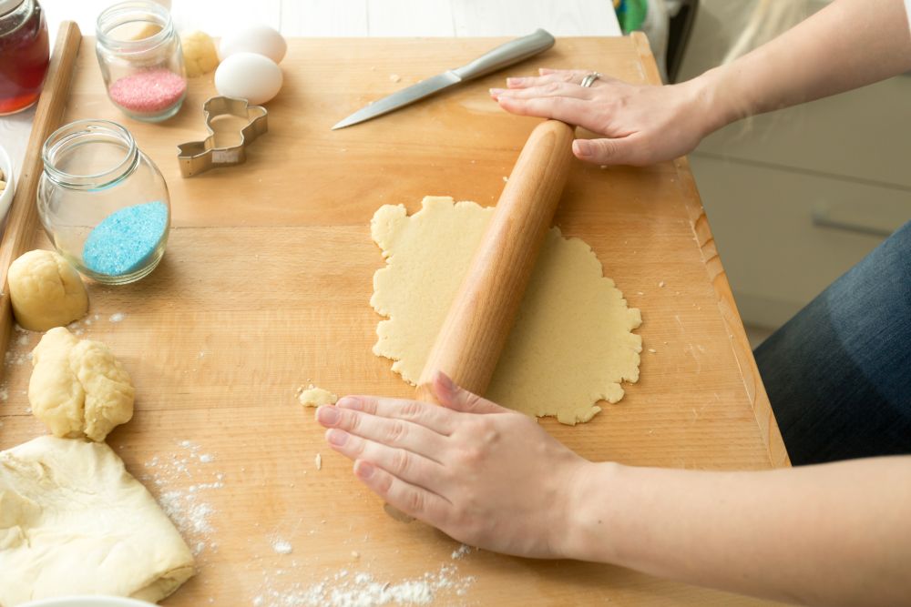 Closeup photo of woman making dough for cookies on wooden board