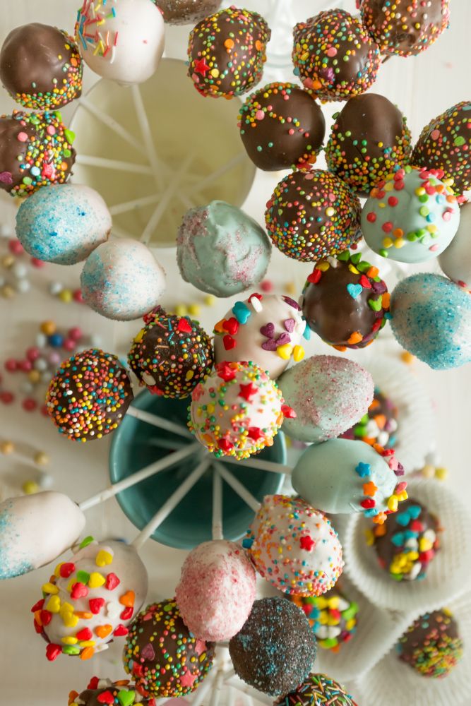 Toned top view shot of colorful cake pops against white wooden background