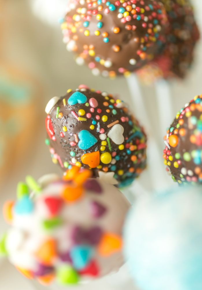 Closeup of beautiful colorful cake pops on white wooden background