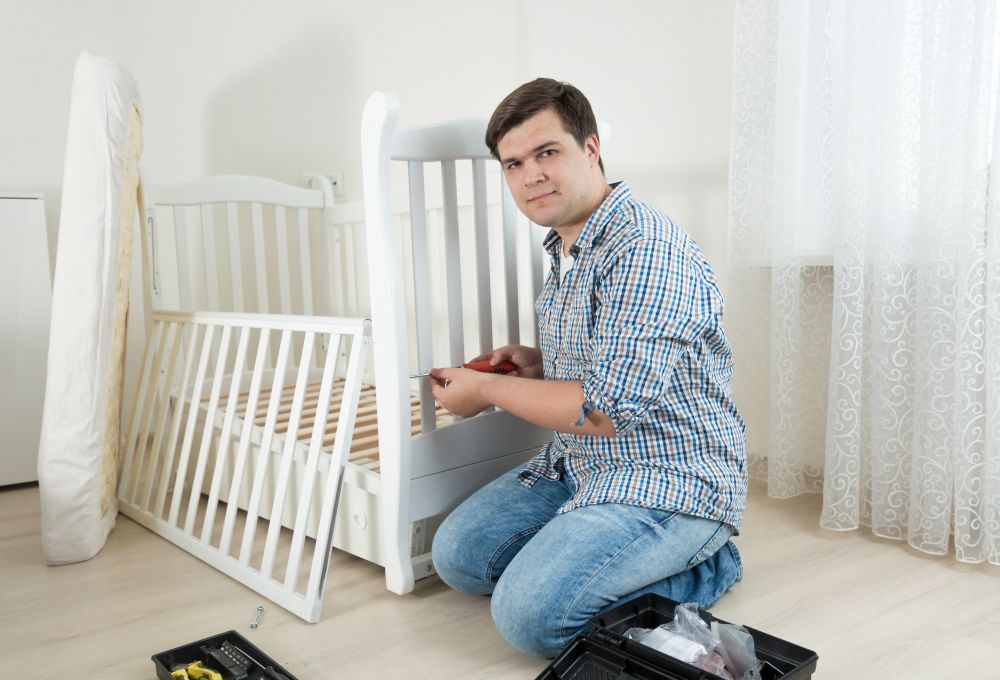 Handyman sitting on floor at empty room and assembling new furniture