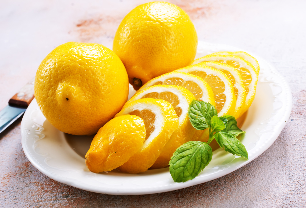 Fresh lemons and lemon slice on metal plate