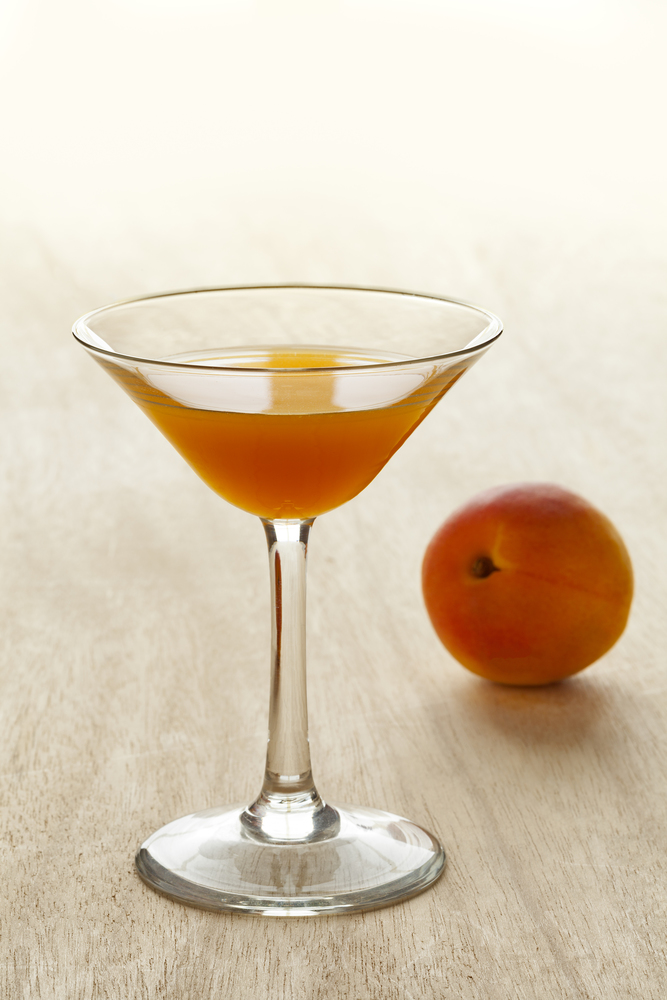 Glass of apricot liqueur and fresh fruit on the background
