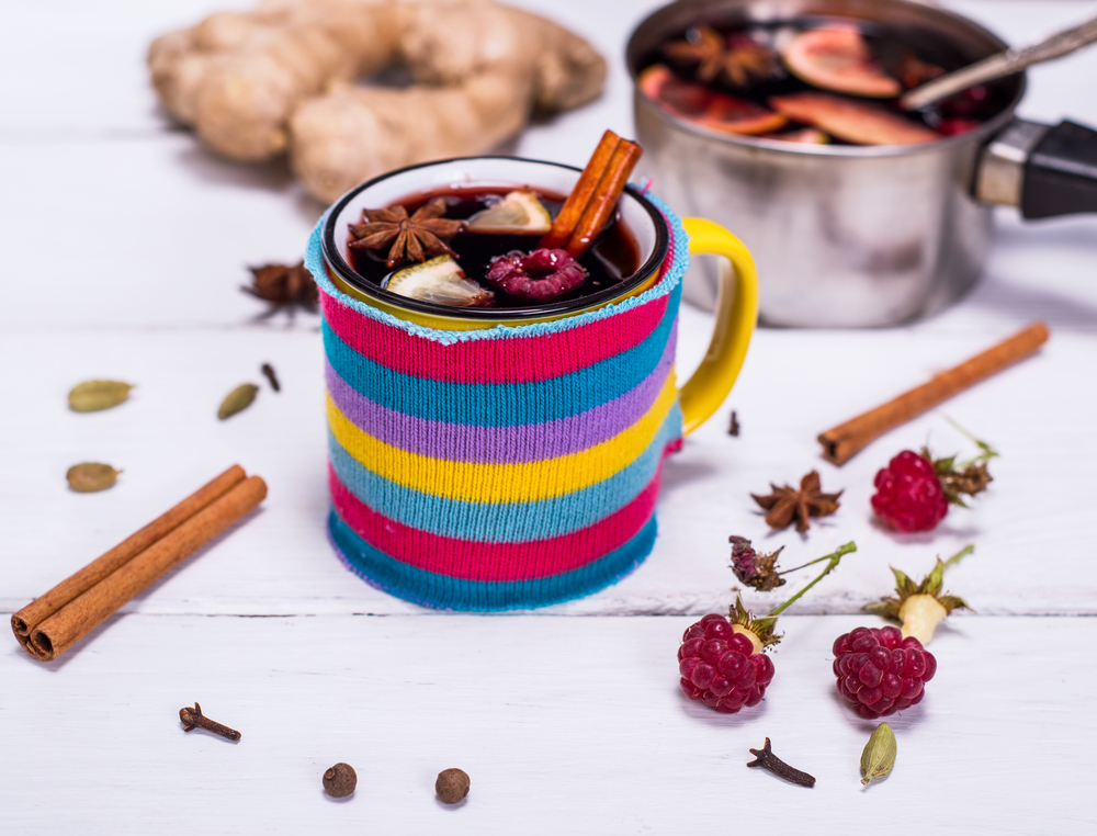 hot mulled wine in a mug and spices on a white wooden background