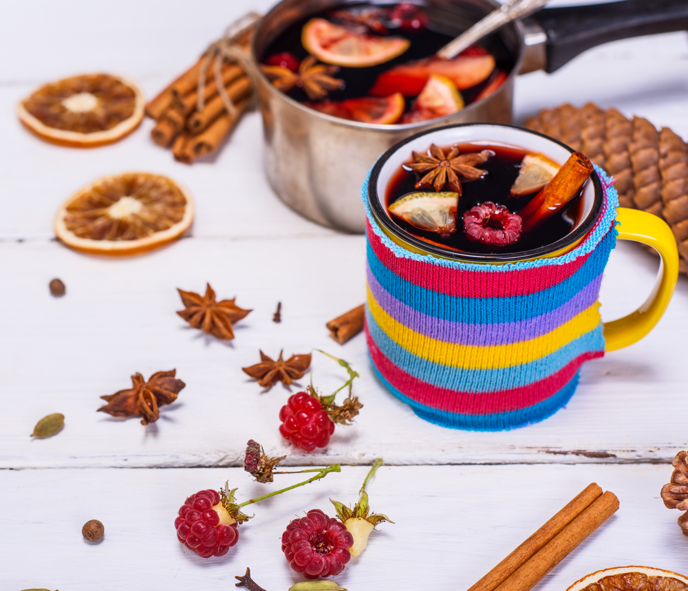 mulled wine in a cup and ingredients for preparation of alcohol on a white wooden table