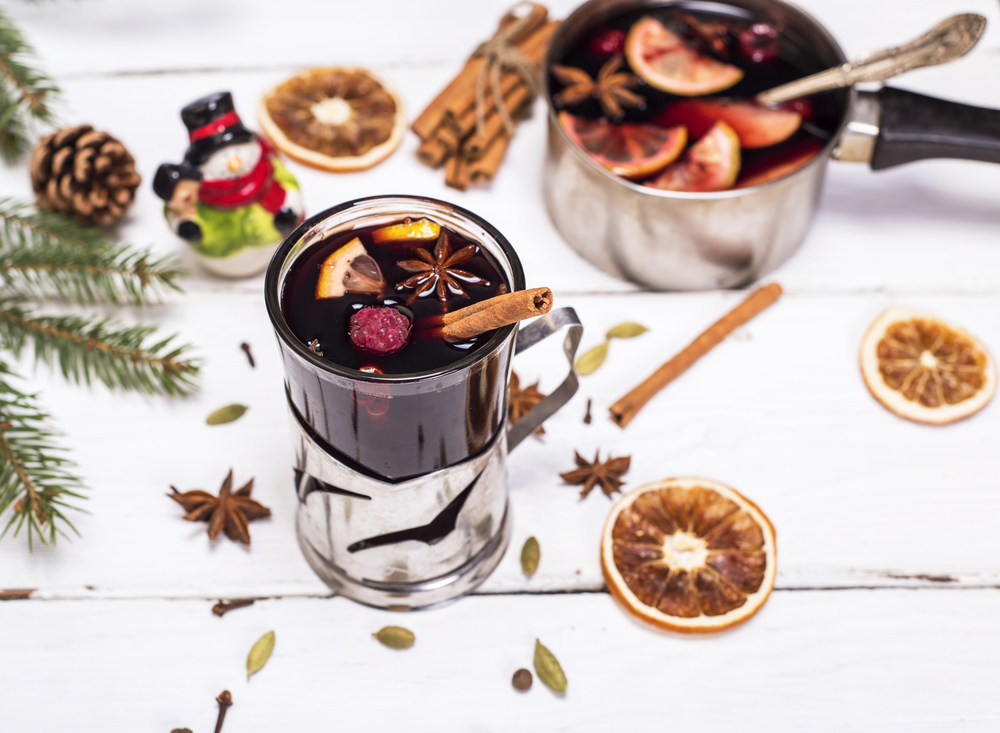mulled wine in a glass with an iron cup holder on a white wooden background