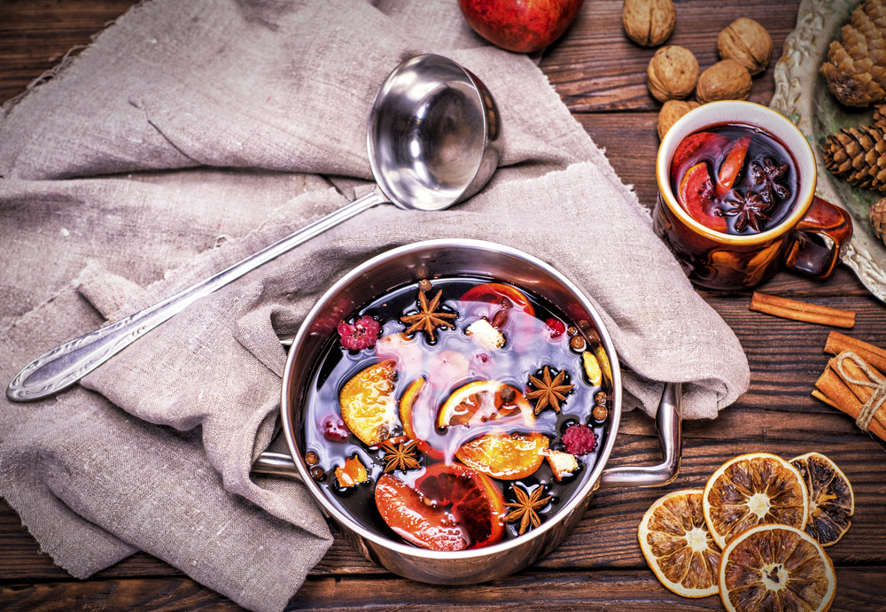 mulled wine in a saucepan on a brown wooden background, top view