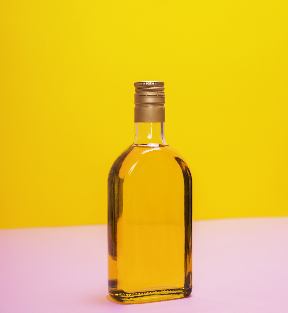 glass bottle with yellow liquid on a yellow background
