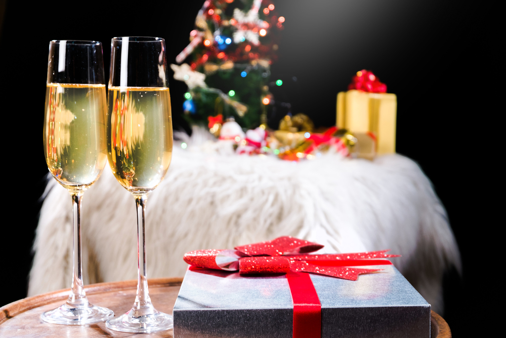 two champagne glasses and gift boxes with christmas tree on background
