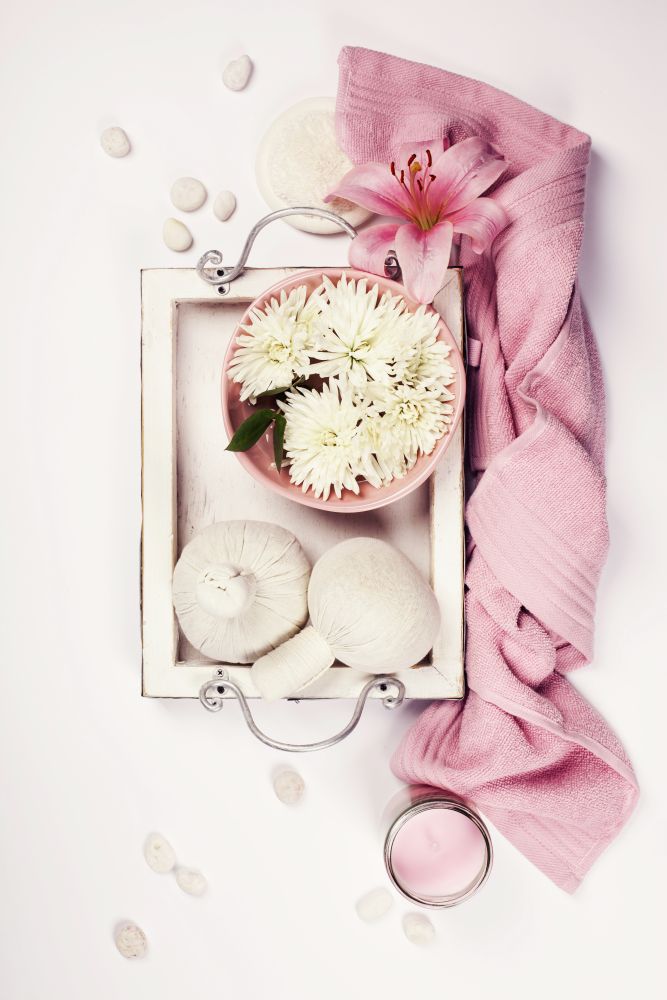 Spa setting with floating flowers and body care and cosmetic tools on shabby chic white background, top view. Wellness concept