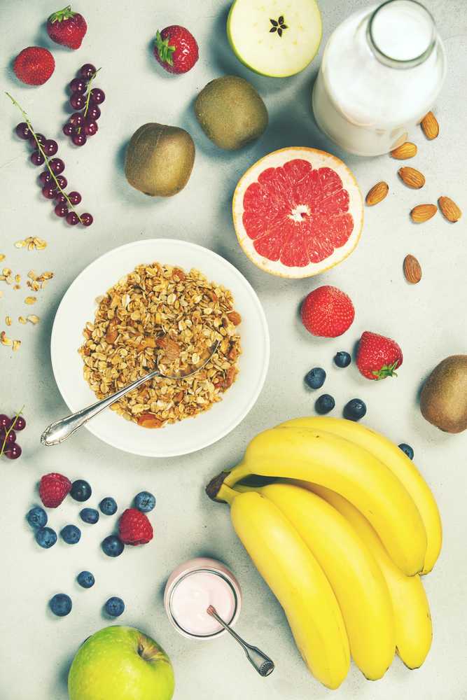 Healthy breakfast ingredients. Bowl of oat granola, almond milk, fresh fruits, berries, yogurt, juice and coffee. Top view