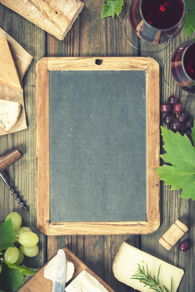 Food frame. Wine and snack set with red wine in glasses, meat variety, bread, cheese and grape on   rustic wooden background, top view, copy space in center
