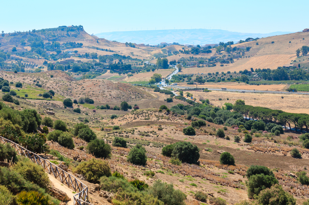 View to road, gardens and mountain from famous ancient ruins in Valley of Temples, Agrigento, Sicily, Italy.
