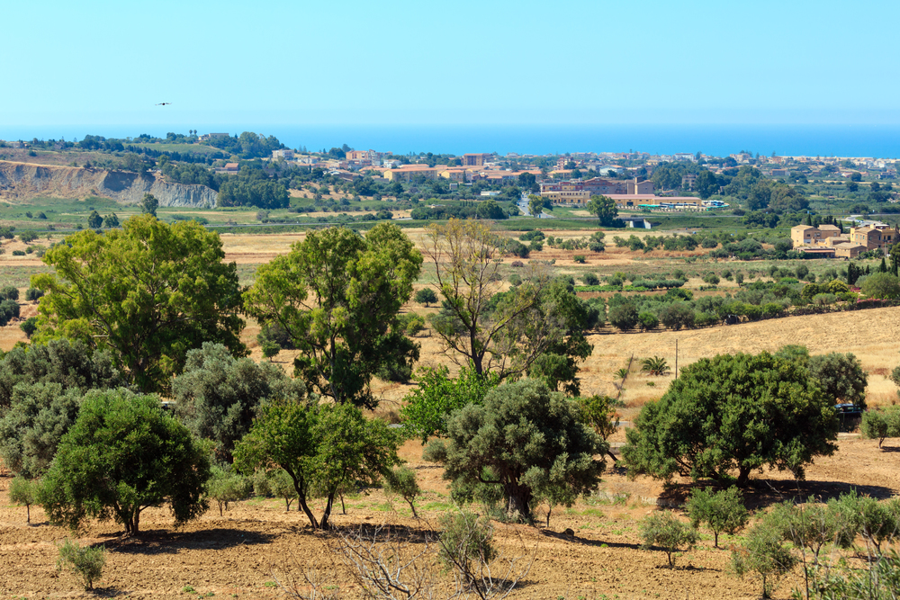 View to gardens, town and sea from famous ancient ruins in Valley of Temples, Agrigento, Sicily, Italy.