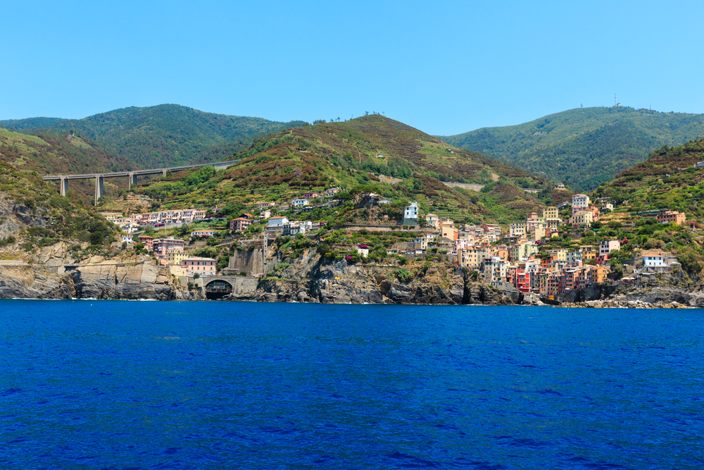 Beautiful summer Manarola view from excursion ship. One of five famous villages of Cinque Terre National Park in Liguria, Italy, suspended between Ligurian sea and land on sheer cliffs.