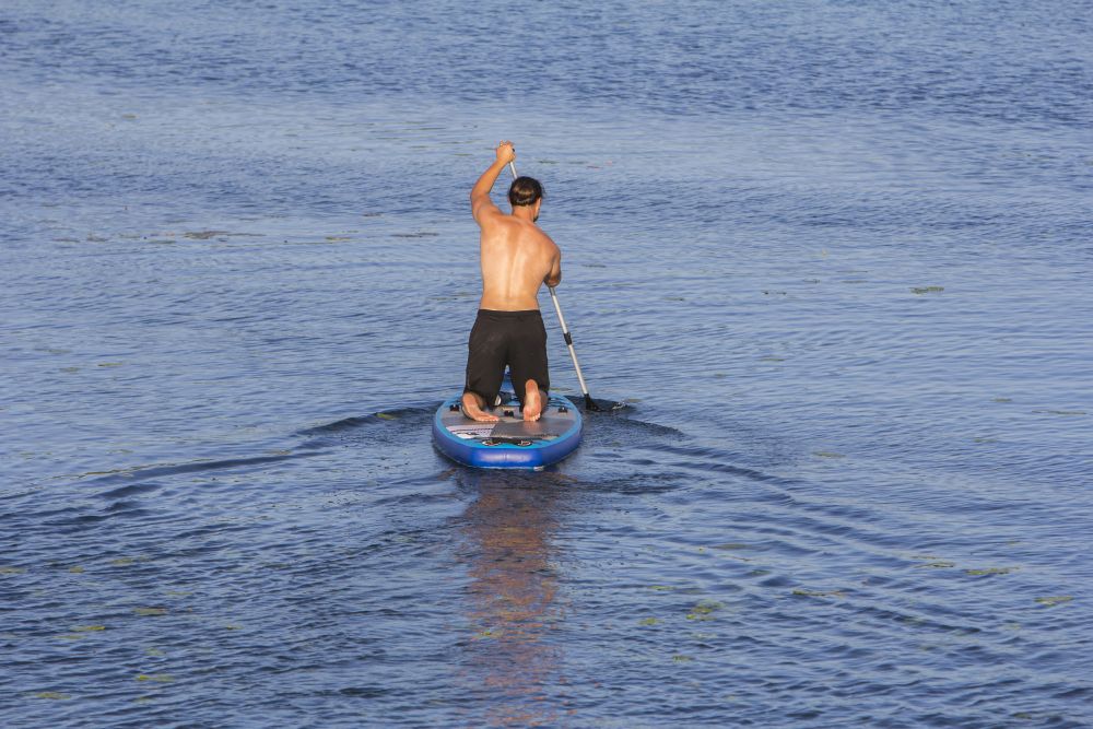 Man on Paddle Board paddling out to lake