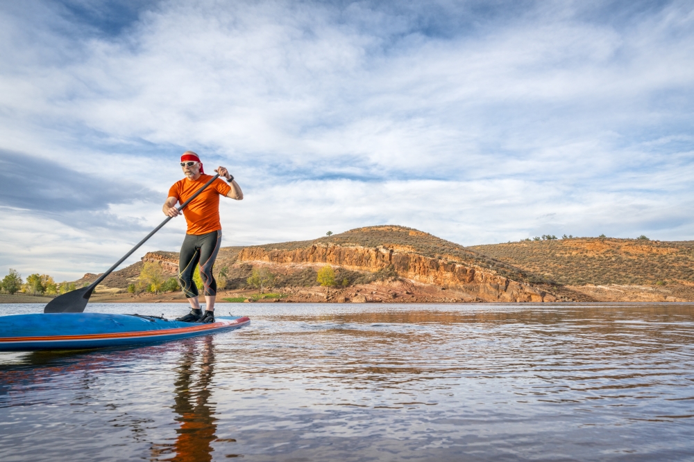 A senior male paddling on a stand up paddleboard on a calm mountain lake - Horsetooth Reservoir near Fort Collins, Colorado, fall scenery