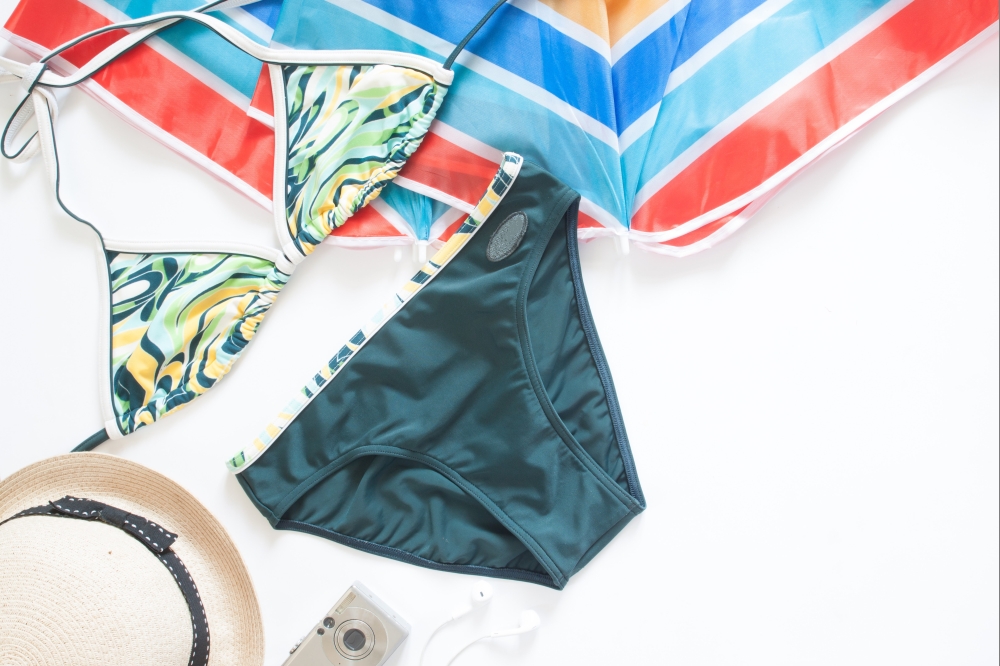 Bikini in green color with summer items, Flat lay of summer concept