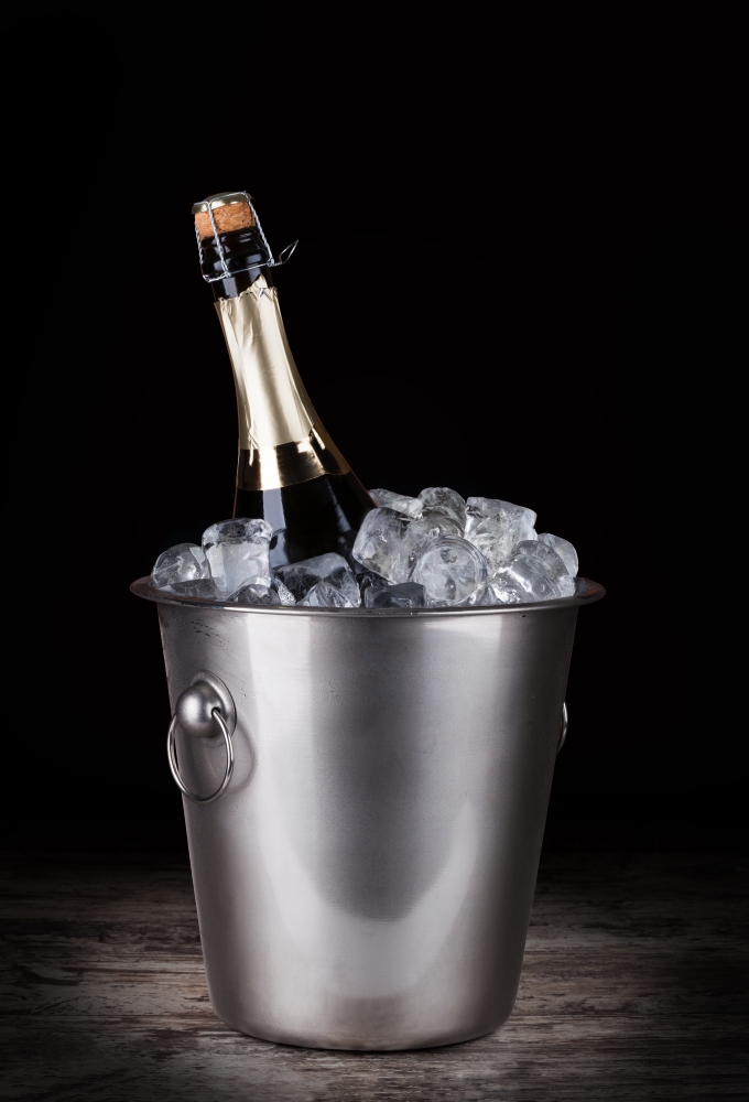Champagne bottle in a bucket with ice. Champagne bottle in a bucket with ice on the dark background