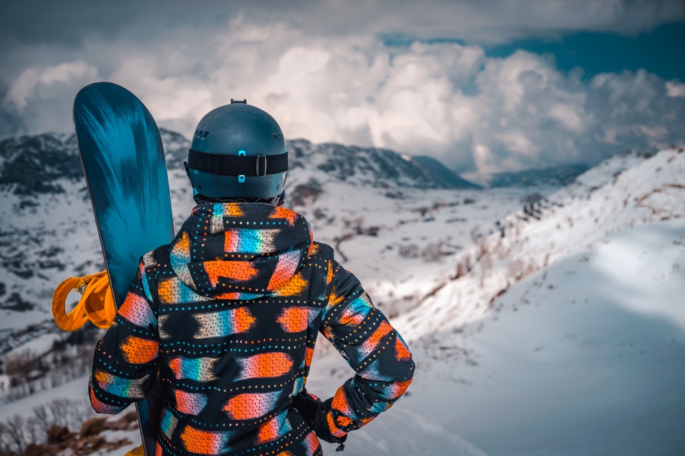 Rear View Of a Female Snowboarder Enjoying Amazing View of a Snowy Mountains. Active Healthy Lifestyle. Spending Winter Holidays on Ski Resort.