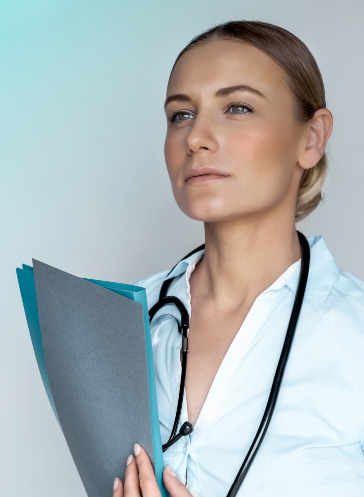 Serious woman doctor holding documents, isolated on blue background, copy space, thoughtfully looking away, health care industry