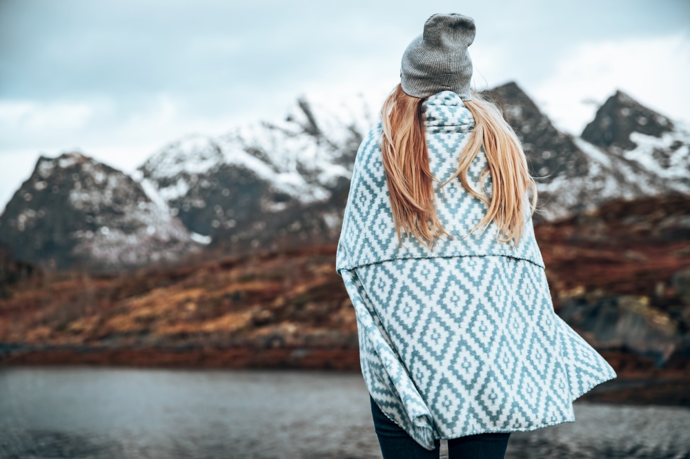 Back Side View of Female Wrapped in Blanket Enjoying Beautiful Landscape of a Majestic Mountains. Amazing Nature of Lofoten Islands. Norway