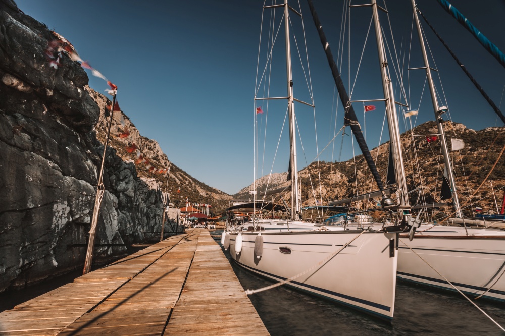 Photo of a Moored Sailboats in the Harbor in Sunny Day. Nice Warm Weather on Beach Resort. Active Summer Vacation. Turkey. Moored Sailboats in the Harbor