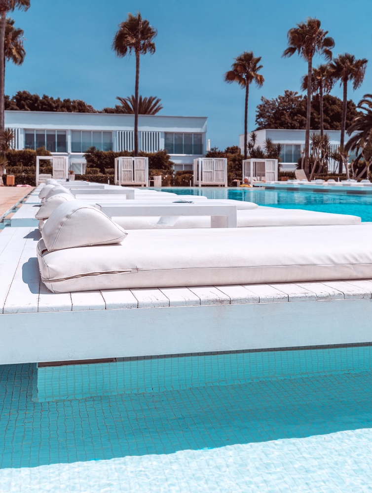 Luxury beach resort, gorgeous white sunbeds situated near the pool with transparent blue water, perfect place for summer vacation, Cyprus island