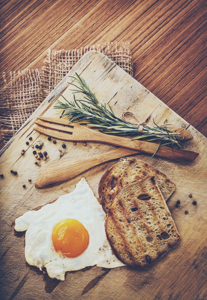 Breakfast. Tasty Fried Egg with Two Slice of Bread Decorated with Rosemary Branches an Served with Wooden Utensil and Canvas Napkin. Rustic Style.. Tasty Morning Fried Egg