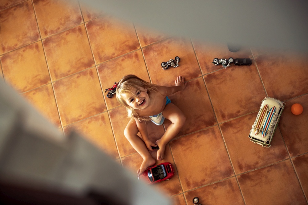 Top view from stairs on the little baby boy playing with toys, spy on the baby when he plays, spending happy time at home