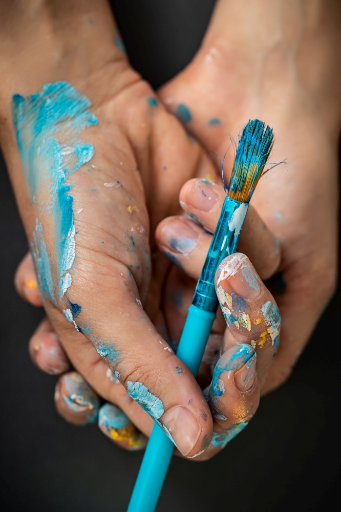 Conceptual photo of an art inspiration, artist&rsquo;s hands staind with paint, holding paintbrush, time for creativity