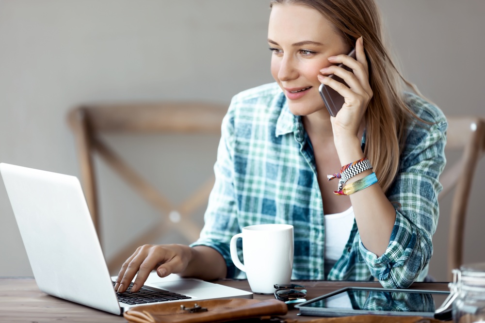 Portrait of a Beautiful Female Talking on the Phone and Drinking Morning Coffee near the Notebook. Young Successful Businesswoman Working from Home. Studying Online.
