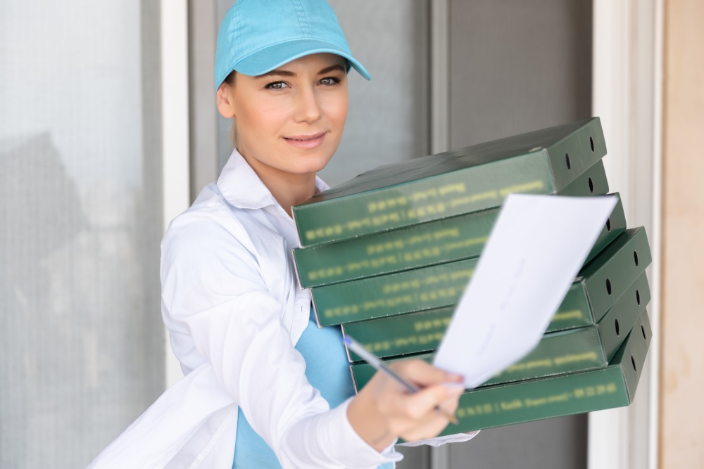 Portrait of a Pretty Girl Wearing Uniform Delivering Pizza to the Customer. Service Occupation. Fast Food. Tasty Eating. Summer Job. Door to Door Delivery.