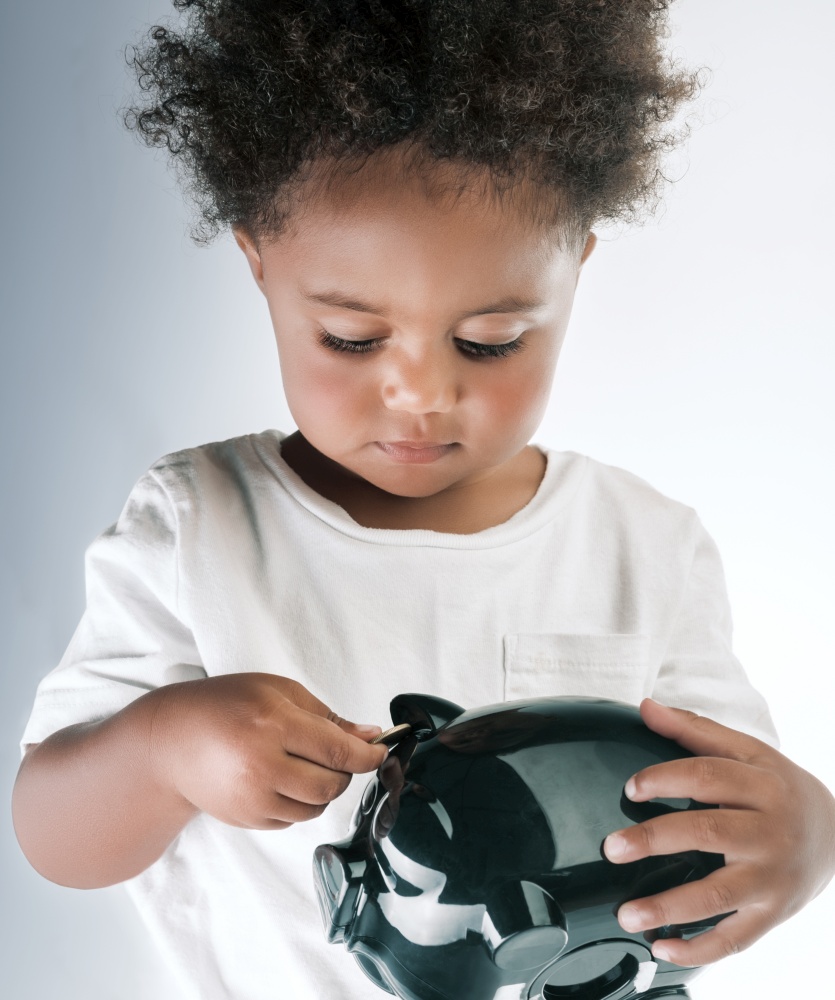 Portrait of a Cute Little African American Boy With Piggy Bank in Hands. Isolated over Empty Gray White Background. Investment in the Future. Saving Money Concept.