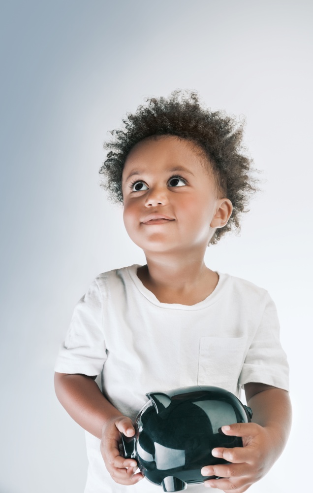 Portrait of a Cute Little African American Boy Model With Piggy Bank in Hands. Isolated on Clean Gray White Background. Investment in the Future. Saving Money Concept.